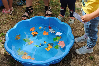 Eine blaue große Plastikmuschen, in der der sich Spielzeugtiere befinden und in Wasser schwimmen.