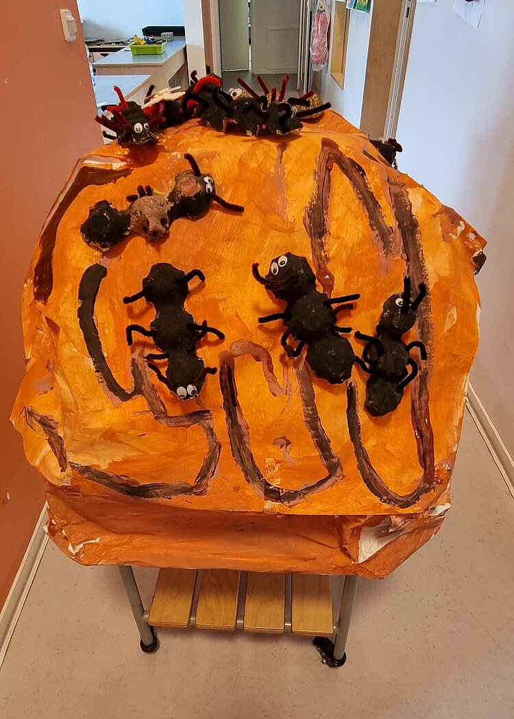 Ein aus Pappmache gebasteltes Modell eines Ameisenhügels auf einem Tisch mit Rollen.
